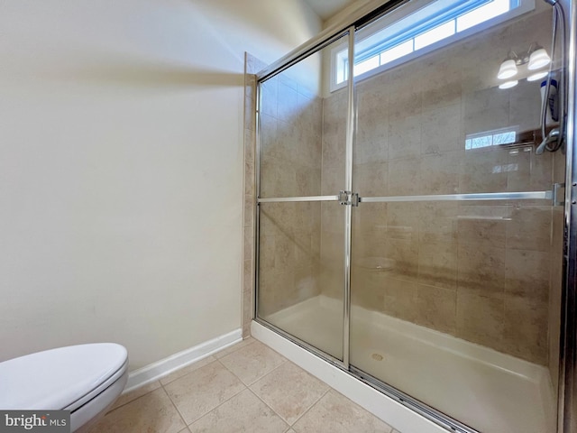 bathroom featuring tile patterned floors, a shower stall, toilet, and baseboards