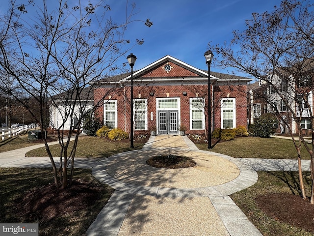 colonial home featuring brick siding, french doors, and concrete driveway