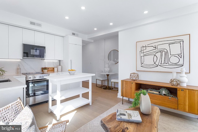 kitchen with visible vents, black microwave, stainless steel electric range oven, light countertops, and open shelves