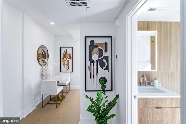 interior space featuring light wood finished floors, visible vents, baseboards, and a sink