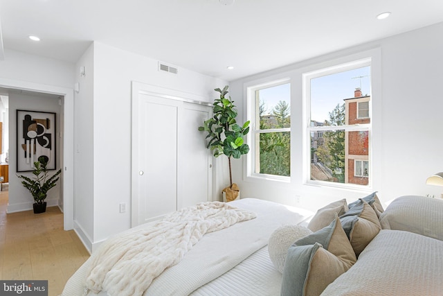 bedroom featuring recessed lighting, light wood-style floors, visible vents, and a closet