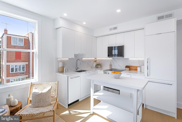 kitchen with a sink, visible vents, tasteful backsplash, and light countertops