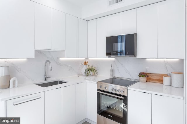 kitchen featuring visible vents, a sink, white cabinetry, black microwave, and stainless steel electric range oven