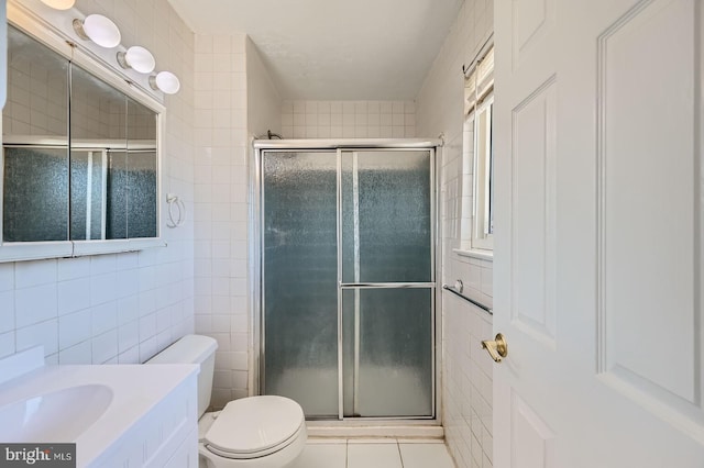 full bathroom featuring tile patterned flooring, toilet, vanity, a stall shower, and tile walls