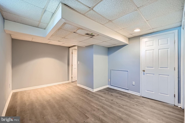 finished basement featuring wood finished floors, baseboards, and a drop ceiling