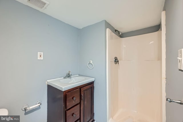 bathroom featuring visible vents, toilet, a stall shower, and vanity