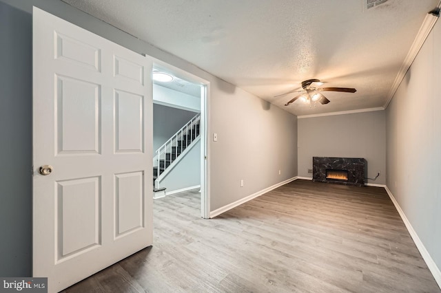 interior space with a textured ceiling, wood finished floors, a fireplace, baseboards, and stairs