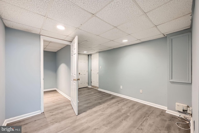 finished basement featuring a drop ceiling, baseboards, and wood finished floors