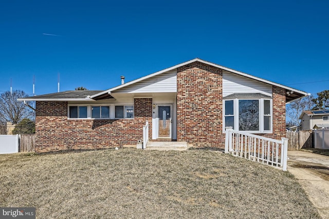 view of front of property with brick siding, a front yard, and fence