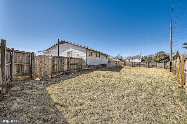 view of yard with a gate, a fenced backyard, and central AC