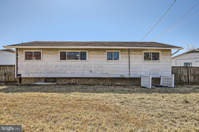 rear view of property with a lawn and fence