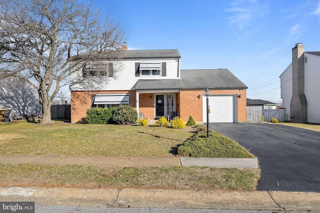 traditional home featuring brick siding, an attached garage, fence, a front yard, and driveway