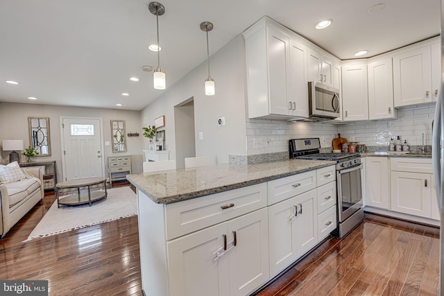 kitchen with open floor plan, white cabinets, appliances with stainless steel finishes, and dark wood-style flooring