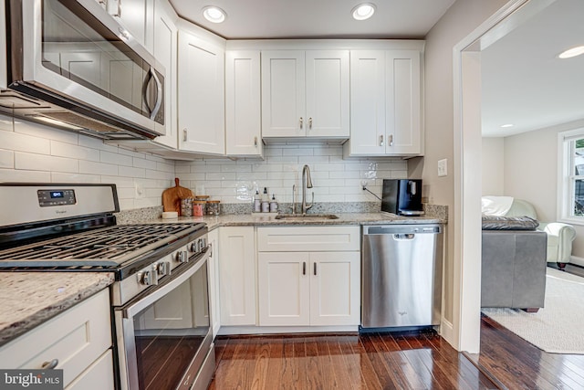 kitchen with dark wood finished floors, white cabinets, appliances with stainless steel finishes, and a sink