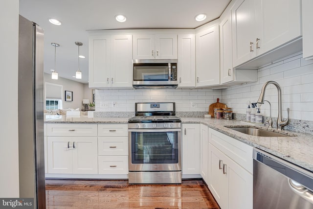 kitchen featuring decorative backsplash, appliances with stainless steel finishes, white cabinetry, and a sink