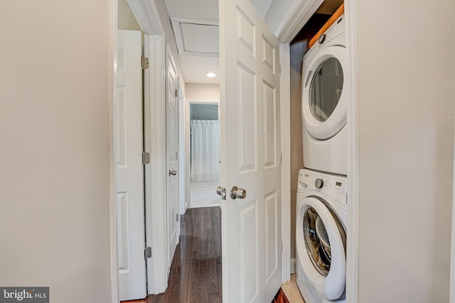 laundry room featuring stacked washer / drying machine, dark wood-type flooring, and laundry area