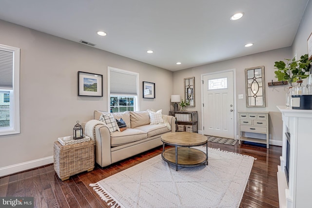 living area with visible vents, baseboards, plenty of natural light, and dark wood finished floors