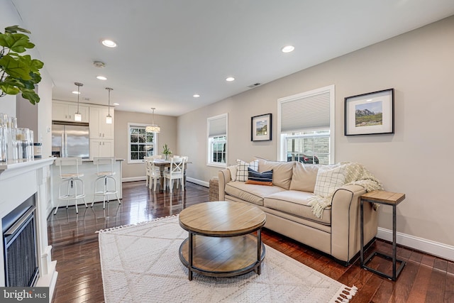 living room with dark wood-style floors, visible vents, recessed lighting, and baseboards