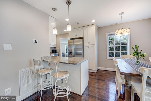 kitchen with visible vents, stainless steel fridge, dark wood-style floors, and white cabinetry