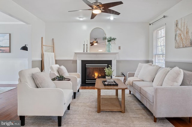 living area with a fireplace with flush hearth, wood finished floors, and ceiling fan