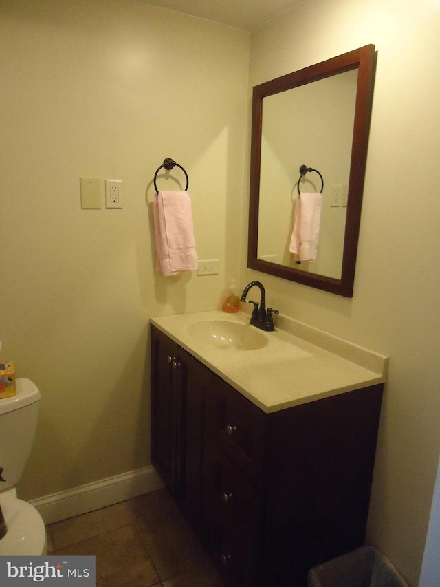 half bath featuring baseboards, toilet, vanity, and tile patterned flooring