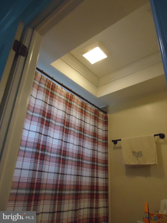 bathroom with a shower with shower curtain, a raised ceiling, and ornamental molding