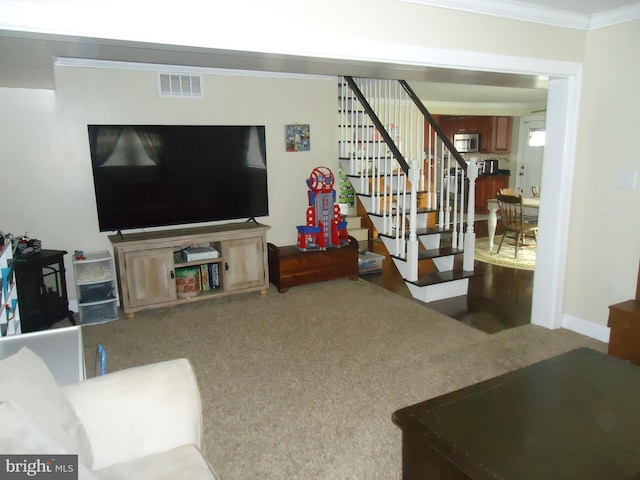 carpeted living area featuring visible vents, baseboards, crown molding, and stairway