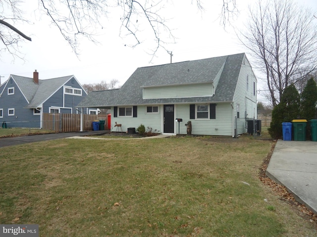 view of front of property featuring an attached carport, fence, aphalt driveway, roof with shingles, and a front yard