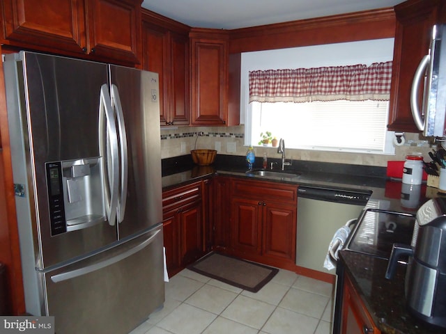 kitchen with a sink, decorative backsplash, light tile patterned flooring, stainless steel appliances, and reddish brown cabinets