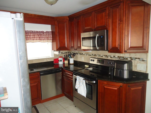 kitchen with light tile patterned flooring, decorative backsplash, appliances with stainless steel finishes, and reddish brown cabinets