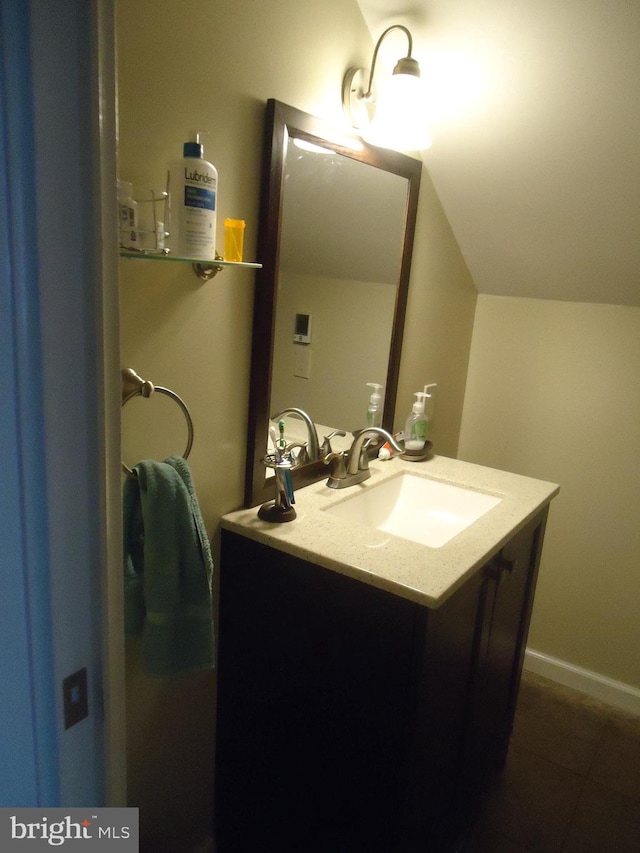 bathroom with vanity, lofted ceiling, and baseboards