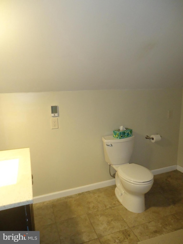 bathroom with vanity, vaulted ceiling, toilet, and baseboards