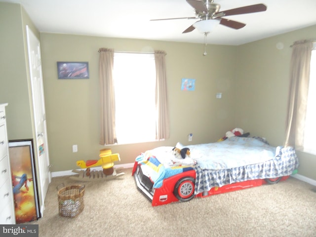 carpeted bedroom featuring baseboards, multiple windows, and ceiling fan