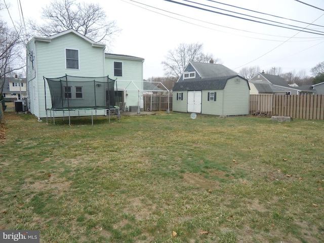 view of yard featuring an outbuilding, a trampoline, central AC, fence, and a storage shed