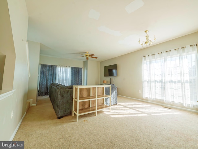 living room with carpet flooring, ceiling fan with notable chandelier, and baseboards