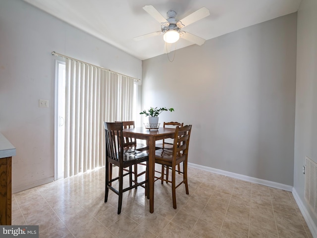 tiled dining area with a ceiling fan and baseboards