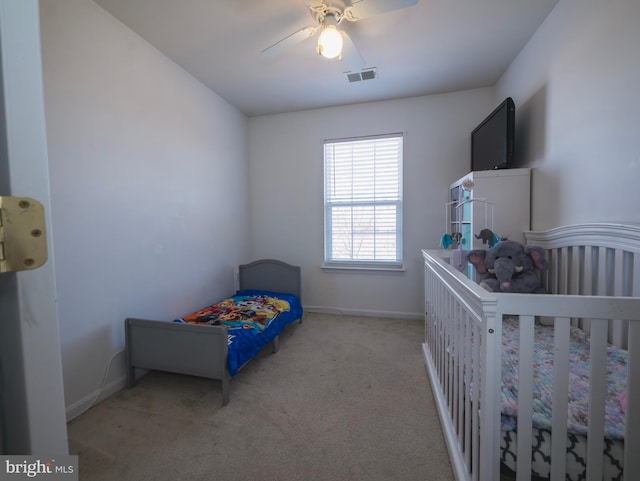 carpeted bedroom with visible vents, baseboards, and a ceiling fan