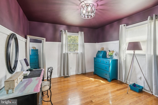 office area with wainscoting, a notable chandelier, and light wood-style flooring