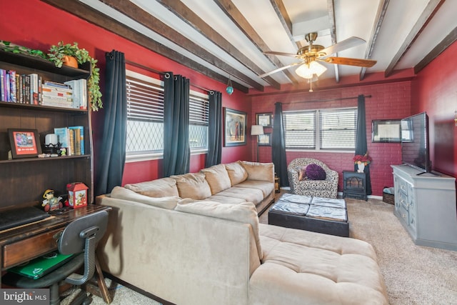 living area with beam ceiling, a wood stove, brick wall, and ceiling fan