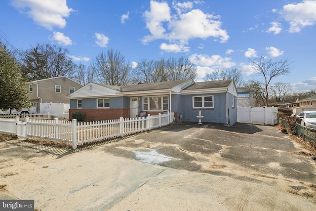 view of front facade featuring a fenced front yard, driveway, and a gate