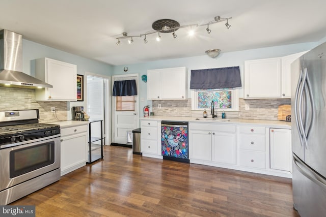 kitchen with light countertops, appliances with stainless steel finishes, dark wood-style floors, wall chimney exhaust hood, and a sink