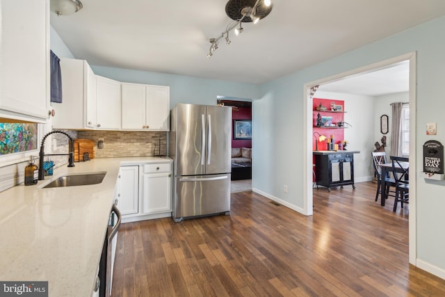 kitchen with backsplash, dark wood-type flooring, freestanding refrigerator, white cabinetry, and a sink