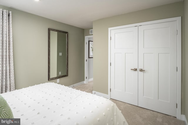 bedroom featuring baseboards, visible vents, a closet, and light carpet