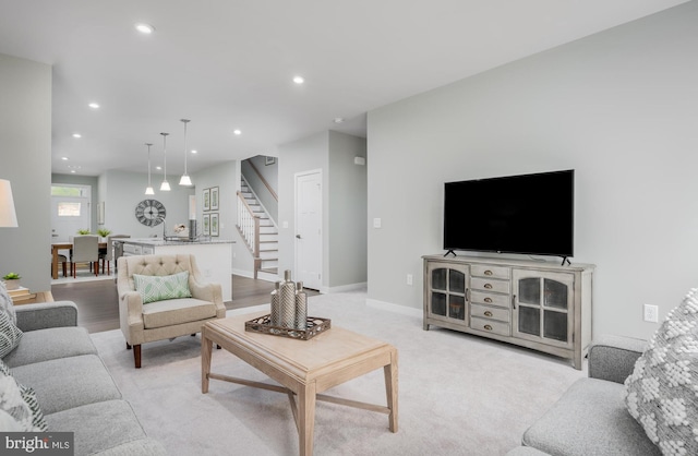 living area with recessed lighting, stairway, baseboards, and light carpet