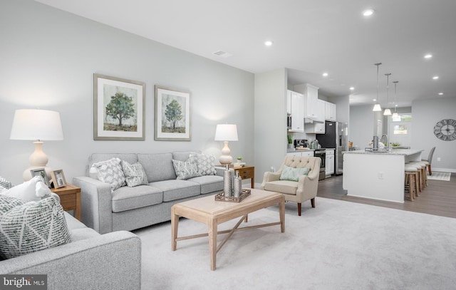 living room with light wood finished floors, visible vents, recessed lighting, and baseboards