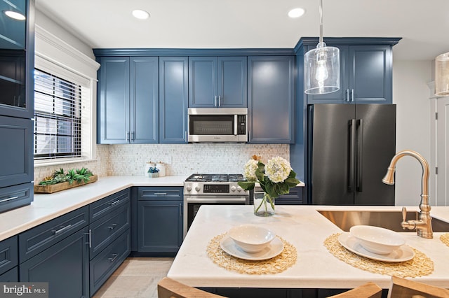 kitchen featuring pendant lighting, light countertops, decorative backsplash, stainless steel appliances, and a sink