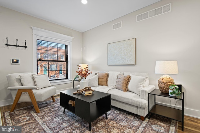 living room featuring visible vents, baseboards, and wood finished floors