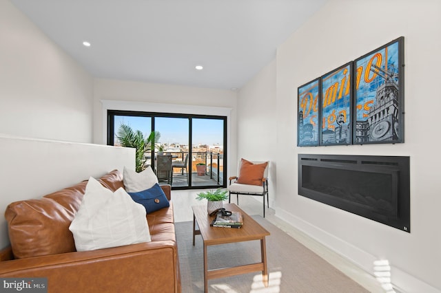 living area with recessed lighting, baseboards, a glass covered fireplace, and wood finished floors