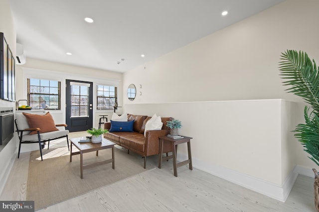 living room with a wall unit AC, light wood-style flooring, recessed lighting, and baseboards