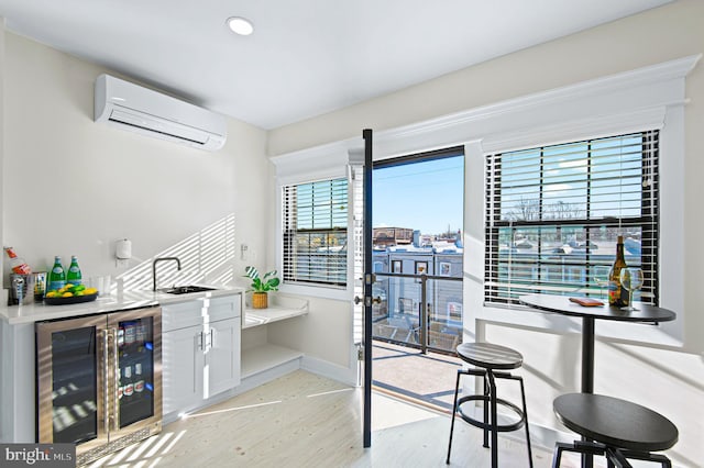 interior space with bar area, baseboards, wine cooler, a wall mounted air conditioner, and light wood-style floors